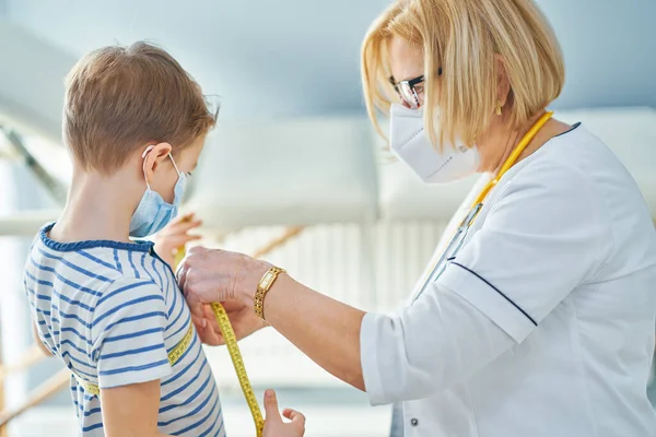 Kinderarts die kleine kinderen onderzoekt in kliniek meetlint — Stockfoto