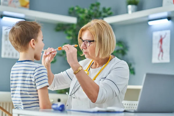 Médico pediatra examinando a niños pequeños en clínica —  Fotos de Stock