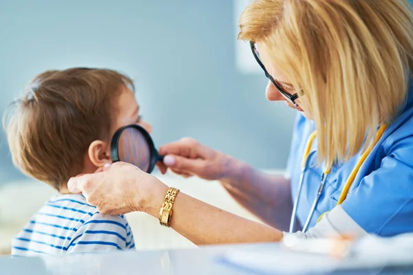 Médico pediatra examinando a niños pequeños en la clínica —  Fotos de Stock