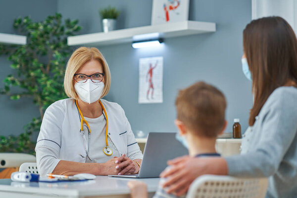 Врач-педиатр осматривает маленьких детей в клинике