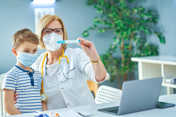 Врач-педиатр осматривает маленьких детей в клинике