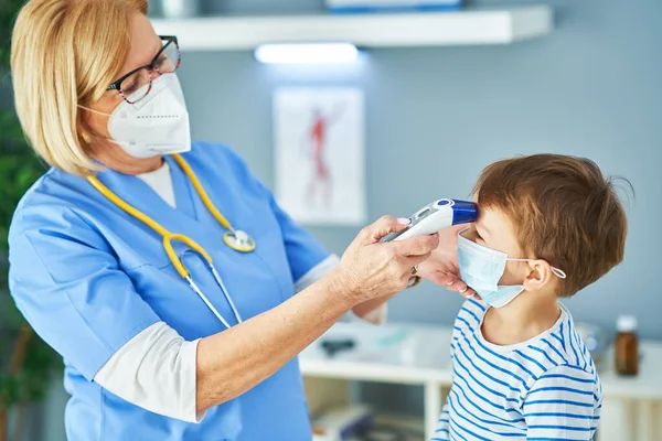 Kinderarts arts onderzoekt kleine kinderen in kliniek temperatuurcontrole — Stockfoto