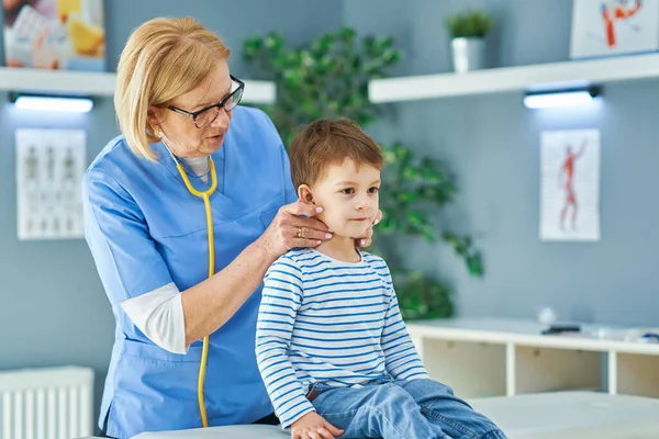 Médico pediatra examinando a niños pequeños en clínica —  Fotos de Stock