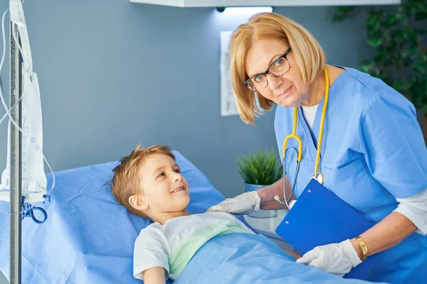 Volwassen vrouw en jonge patiënt in ziekenhuisbed — Stockfoto