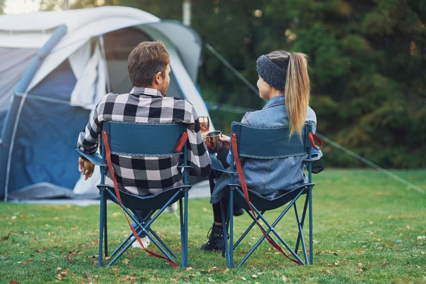 Giovane bella coppia seduta su sedie inf davanti alla tenda in campeggio — Foto Stock