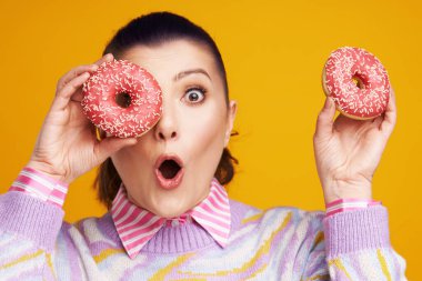 Sarı arka planda, donutlu güzel bir kadın.