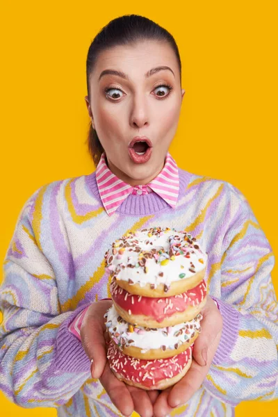 Junge schöne Frau auf gelbem Hintergrund mit Donuts — Stockfoto