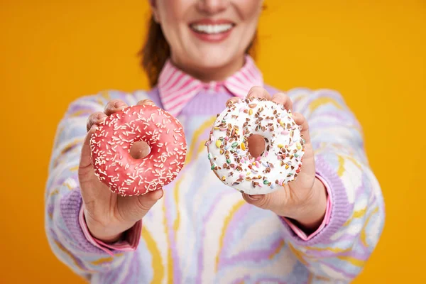 Junge schöne Frau auf gelbem Hintergrund mit Donuts — Stockfoto