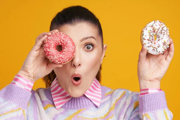 Jonge mooie vrouw over gele achtergrond met donuts — Stockfoto