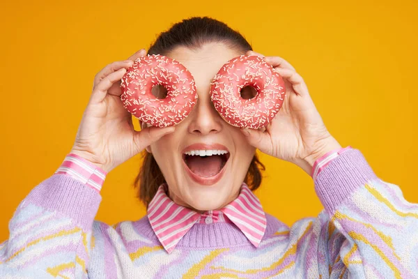 Young beautiful woman over yellow background with donuts — Stock Photo, Image