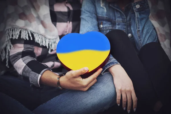 Familjens händer håller ett hjärta i ukrainska färger — Stockfoto