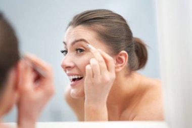 Genç, güzel, esmer kadın banyoda.