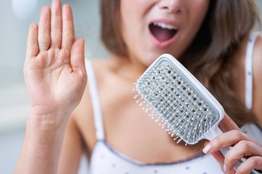 Genç, güzel esmer kadın banyoda saç bakımı yapıyor.