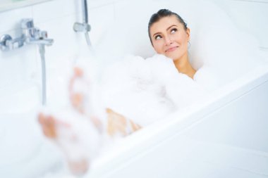 Genç, güzel esmer kadın küvette banyo yapıyor.