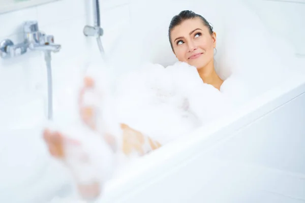 Jovem mulher morena agradável tendo banho na banheira — Fotografia de Stock