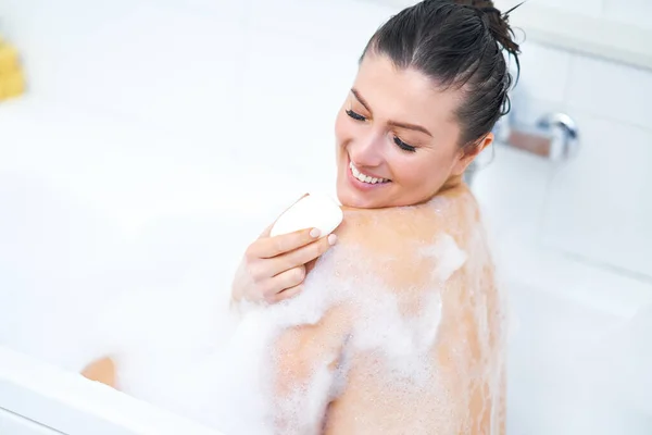 Genç, güzel esmer kadın küvette banyo yapıyor. — Stok fotoğraf