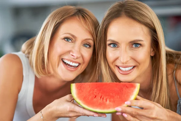 Trevliga två vuxna flickor i köket med vattenmelon — Stockfoto