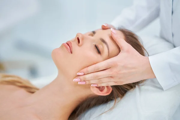 Young nice woman having face massage in spa — Stock Photo, Image