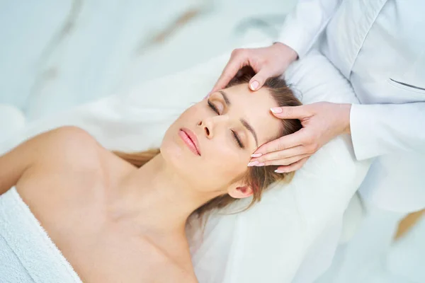 Молода красива жінка має масаж обличчя в спа-центрі — стокове фото