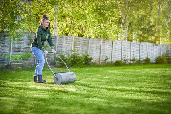 庭で芝生ローラーで働く女性 高品質の写真 — ストック写真
