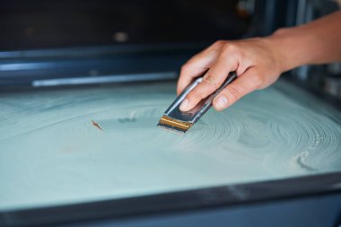 Genç kadın mutfakta fırını temizliyor. Yüksek kalite fotoğraf