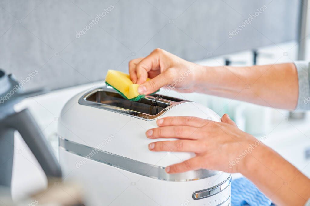 Woman cleaning grill or toaster machine in the kitchen. High quality photo