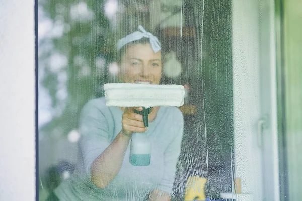 年轻的女人在厨房擦窗户 高质量的照片 — 图库照片