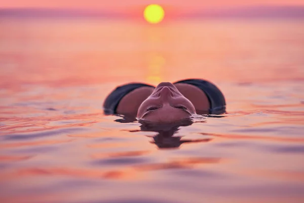 Young woman swimming in the sea on sunrise. High quality photo