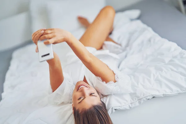 Brünette Sexy Mädchen Auf Dem Bett Mit Telefon Hochwertiges Foto — Stockfoto