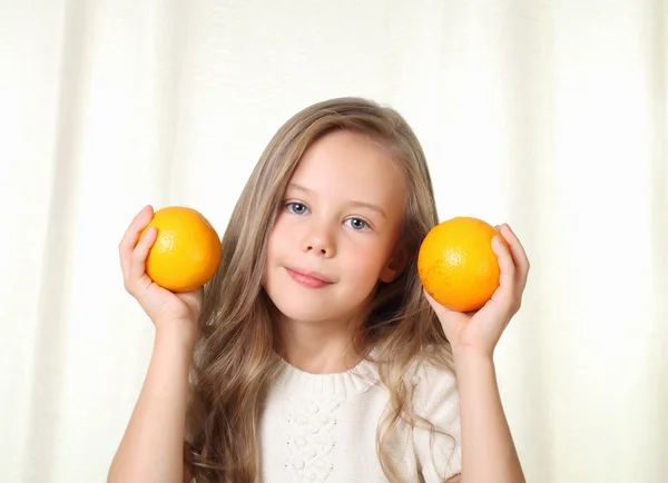 Niña rubia con naranjas sonriendo y mirando a la cámara —  Fotos de Stock