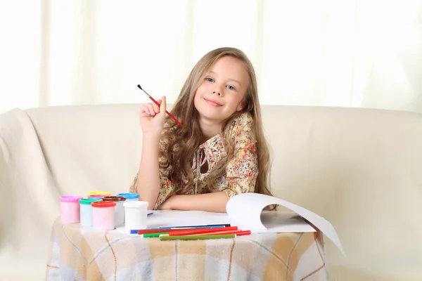 Piccola ragazza bionda che disegna a casa sul divano e guarda sopra — Foto Stock