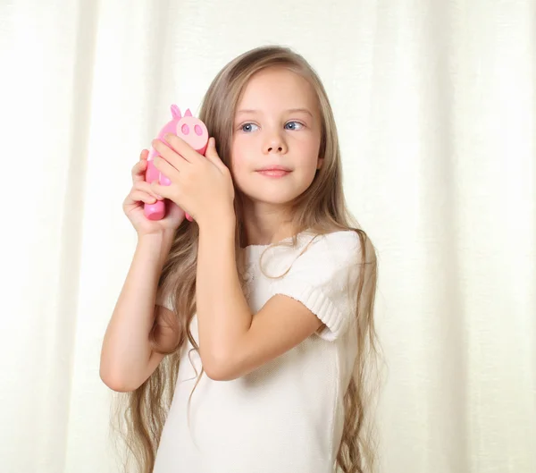 Pequeña chica blong escuchar cuánto dinero en alcancía moneybox — Foto de Stock