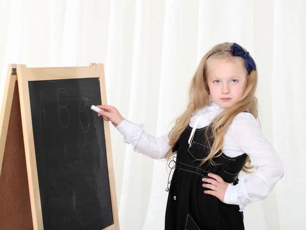 Klein meisje schrijven op zwarte bord met krijt — Stockfoto