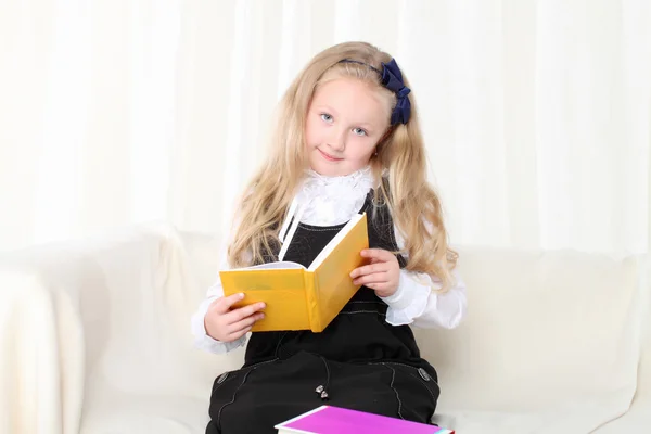 Klein meisje het lezen van een boek zittend op de Bank — Stockfoto