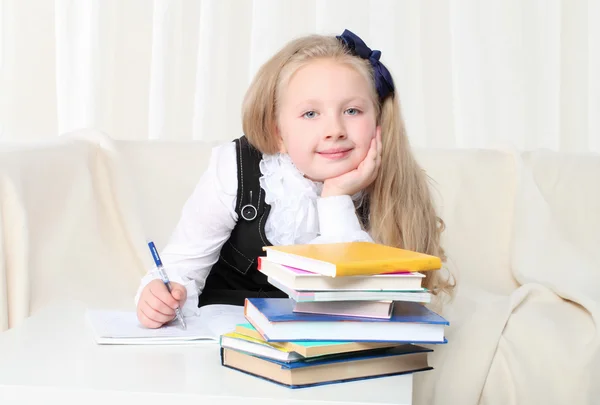 Lilla tjej xD med böcker som sitter på soffan — Stockfoto