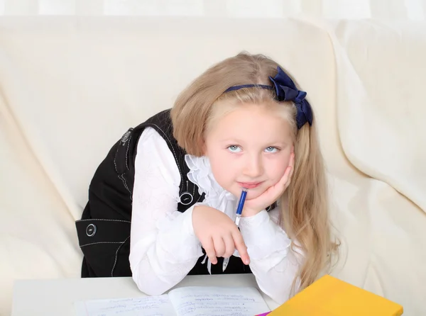 Weinig meisje wtiting met boeken zittend op de Bank — Stockfoto