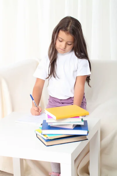 Little girl wtiting with books sitting on sofa — Stock Photo, Image