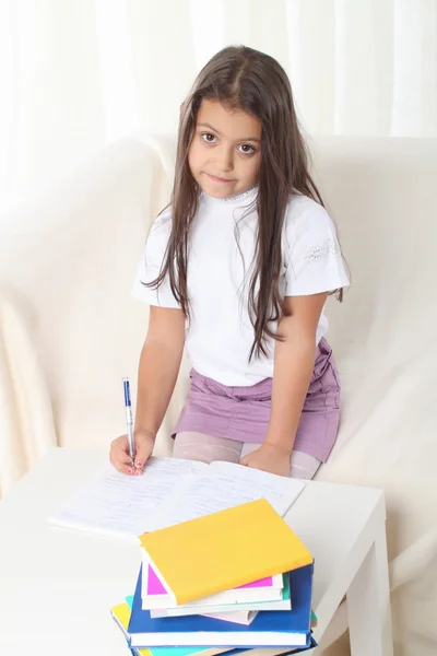 Küçük kız wtiting koltukta oturan kitaplar — Stok fotoğraf