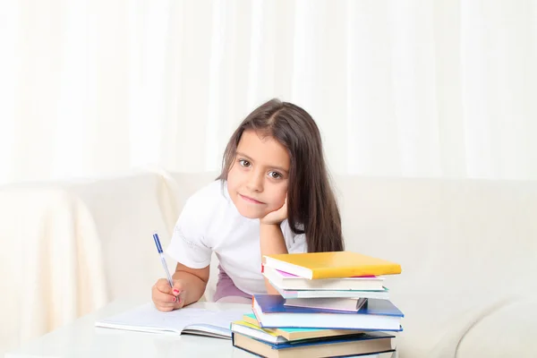 Niña wtiting con libros sentado en el sofá — Foto de Stock