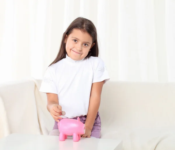 Niña pone moneda en caja de dinero de cerdito —  Fotos de Stock