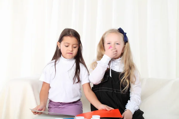 Two little girls sculpting clay on sofa in room — Stock Photo, Image