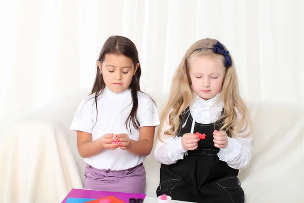 Twee kleine meisjes beeldhouwen klei op sofa in kamer — Stockfoto