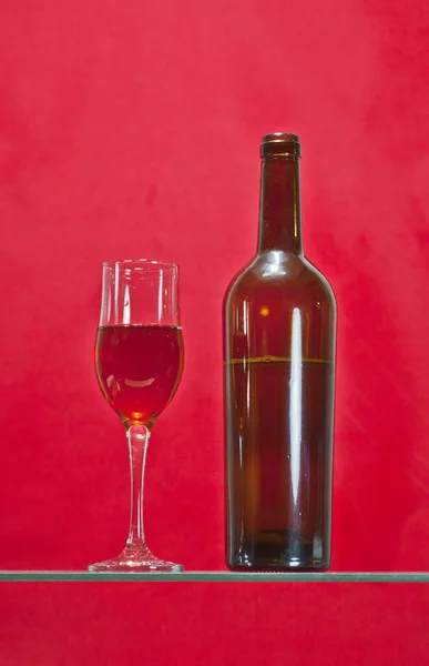 一杯美丽而雅致的葡萄酒里撒满了红酒 旁边是一瓶葡萄酒 — 图库照片