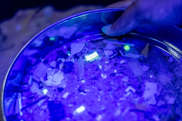 Micro-plastic waste glows under UV light.