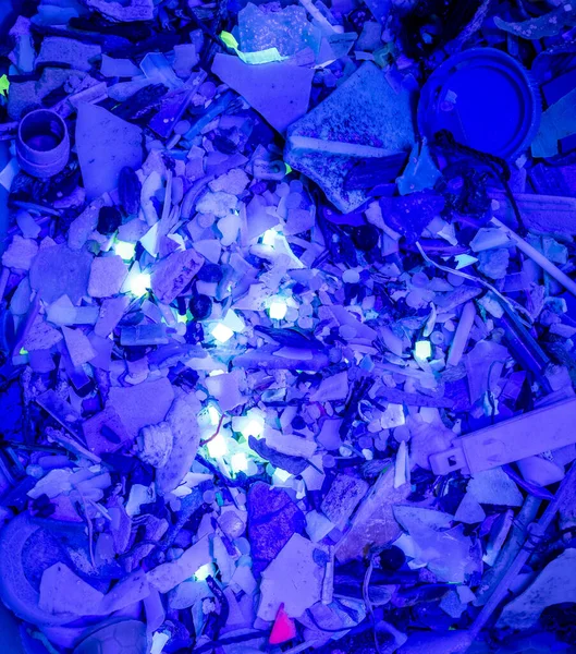 Micro-plastic waste glows under UV light.