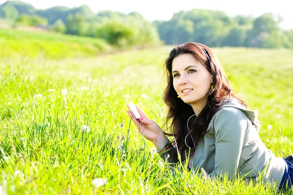 Beautiful girl listening music in the park — Stock Photo, Image