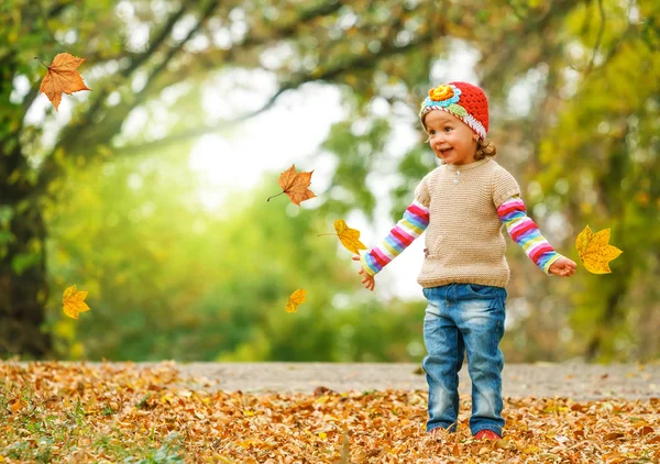 Bambino carino che gioca con le foglie autunnali — Foto Stock