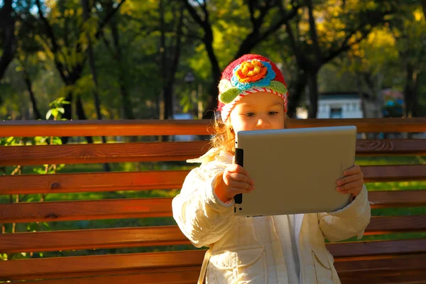 Szczęśliwe dziecko z komputera typu tablet na ławce parku — Zdjęcie stockowe