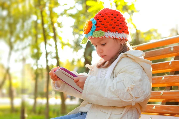 Happy child with tablet PC on a bench park — Stock Photo, Image