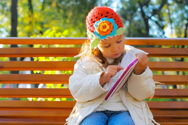 Happy child with tablet PC on a bench park — Stock Photo, Image